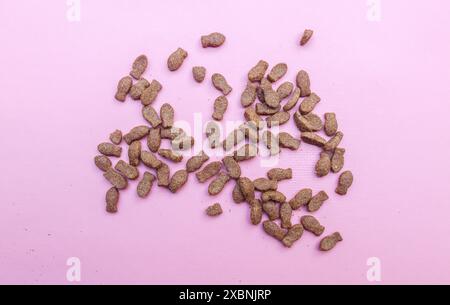 Top view of pieces of kibble for cat food isolated on pink background. Fish-shaped dry cat food Stock Photo