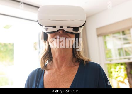 Senior caucasian woman using virtual reality headset, at home Stock Photo