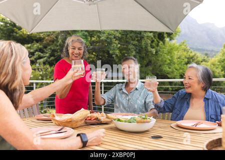 Group of diverse senior women enjoying drinks together at outdoor table Stock Photo