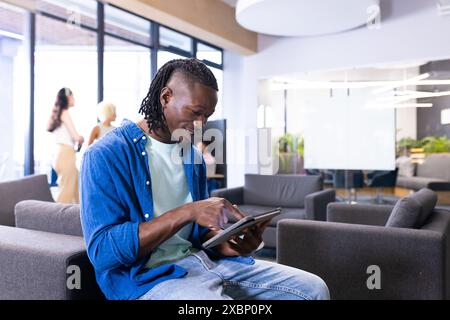 African American man using tablet in modern office lounge for business Stock Photo