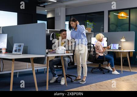 A diverse group of Business colleagues collaborates in a modern office, one showing a tablet Stock Photo
