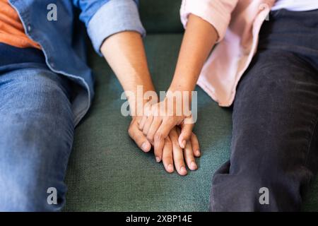 Diverse couple holding hands while sitting together Stock Photo