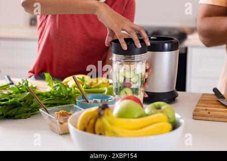 Diverse couple preparing smoothie together in kitchen Stock Photo