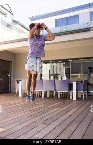 Biracial, Fit man exercising jumping on wooden deck, appearing strong and fit Stock Photo