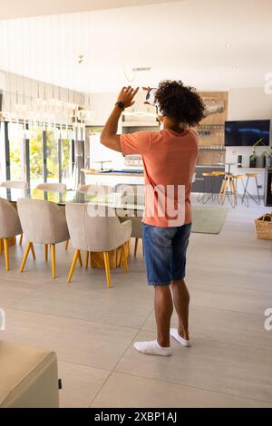 Happy biracial man standing in modern home, using vr headset Stock Photo