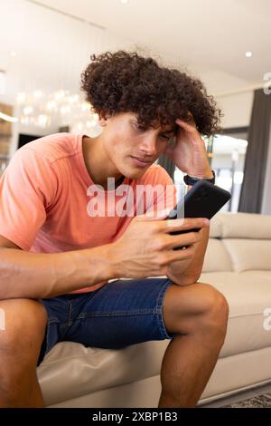 Worried biracial man looking at smartphone Stock Photo