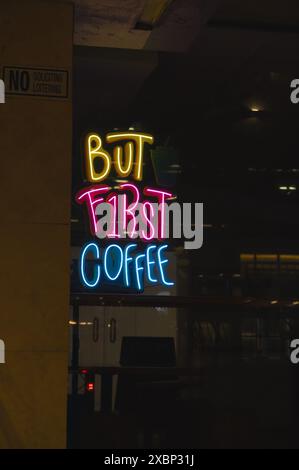 A neon sign reading 'But First Coffee' in a dimly lit cafe or coffee shop. Stock Photo
