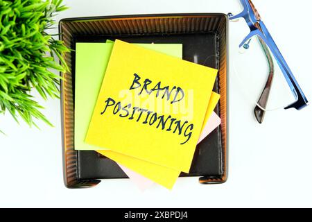 Business branding concept. BRAND POSITIONING text on a yellow sticker in a stand on a white background, top view Stock Photo