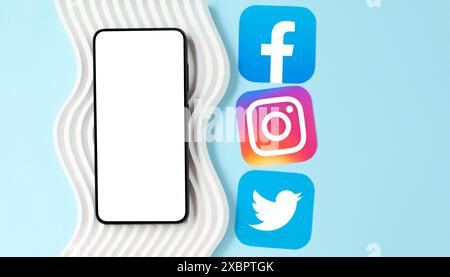 Smartphone with blank screen on decor wave with icons of popular social media apps, on a blue background, social media concept Stock Photo