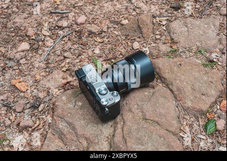 Sony A7c full frame camera with 85mm lens laying on rocky ground in the woods Stock Photo