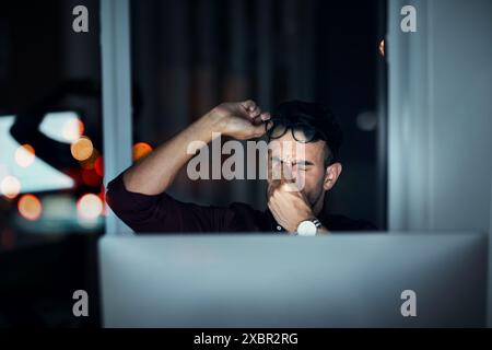 Business man, night and headache on computer with programming burnout, deadline or project fatigue. Tired website developer or programmer with eye Stock Photo