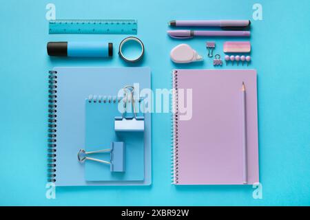 Flat lay composition with notebooks and different stationery on light blue background Stock Photo