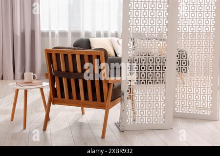 White folding screen, armchair and wooden table in living room Stock ...
