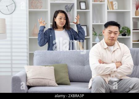 Young couple having an argument in their living room, showcasing stress and relationship issues. Stock Photo