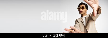 Handsome African American male in tan suit confidently raises hands. Stock Photo