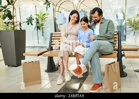 A happy family sitting together on a bench in a bustling shopping mall, enjoying a moment of rest and togetherness. Stock Photo