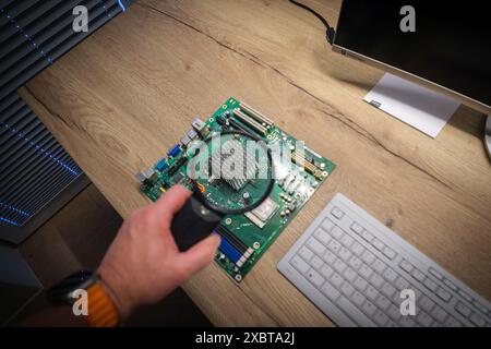 a computer mainboard is examined with a magnifying glass Stock Photo