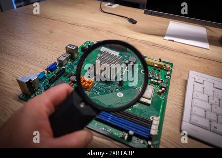 a computer mainboard is examined with a magnifying glass Stock Photo