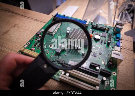 a computer mainboard is examined with a magnifying glass Stock Photo