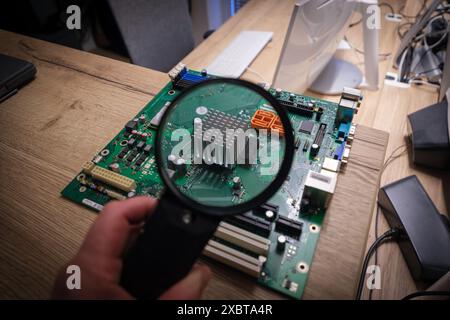 a computer mainboard is examined with a magnifying glass Stock Photo