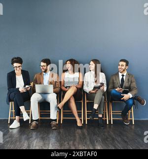 Business people, technology and conversation in waiting room for interview, meeting or recruitment on chair. Hiring, HR and diversity candidates in Stock Photo
