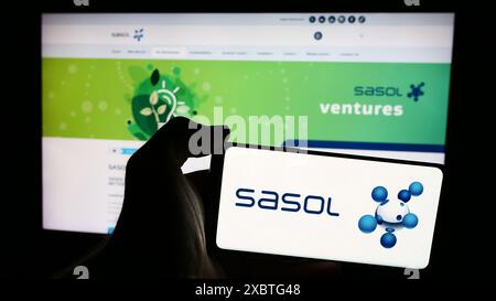 Person holding smartphone with logo of South African energy company Sasol Limited in front of website. Focus on phone display. Stock Photo