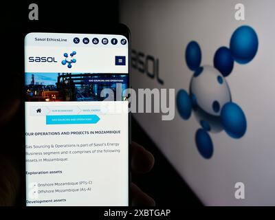 Person holding smartphone with webpage of South African energy company Sasol Limited in front of business logo. Focus on center of phone display. Stock Photo