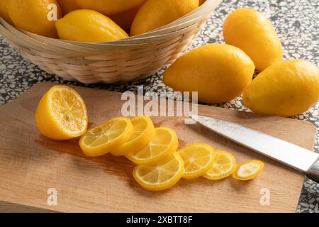 Sliced lemon snack on a cutting board close up and whole ons in the background Stock Photo