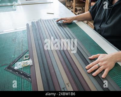 A tanner makes leather belts in a workshop. Close-up of a man's hands. Stock Photo
