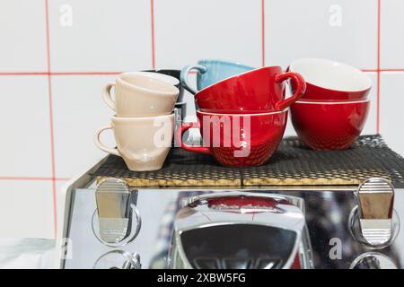 Bright colorful ceramic cups stand on the top of a coffee machine Stock Photo