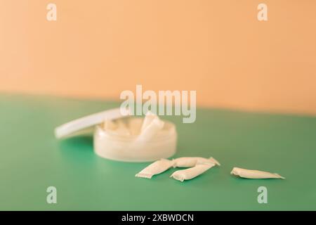 Plastic jar filled with white light snus sachets on a green background Stock Photo