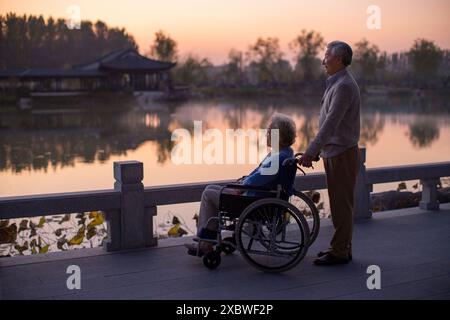 Senior Man Pushing Wife in Wheelchair Stock Photo