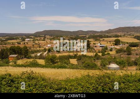 A picturesque view of a rural landscape in Spain, featuring farmhouses nestled amongst rolling hills, green trees, and fields. Stock Photo