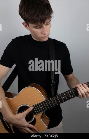 Young man playing guitar in a photo studio. Stock Photo