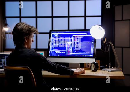 Young male programmer working with computers in office at night Stock Photo