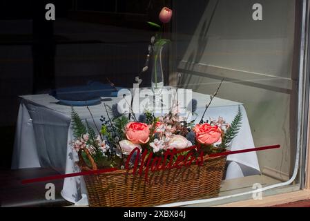 An elegantly set corner table at a window with flower basket and tulip in a vase sets the ambiance at Matteo' Stock Photo