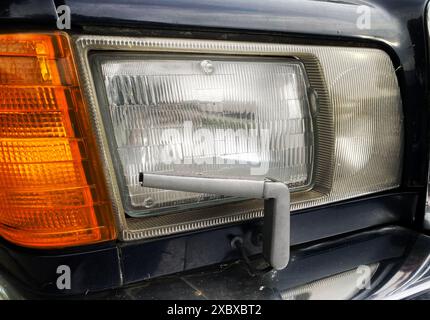 Vintage car headlight wiper, classic car headlights with manual wiper blade on a 1980's or 1990's Mercedes-Benz Stock Photo