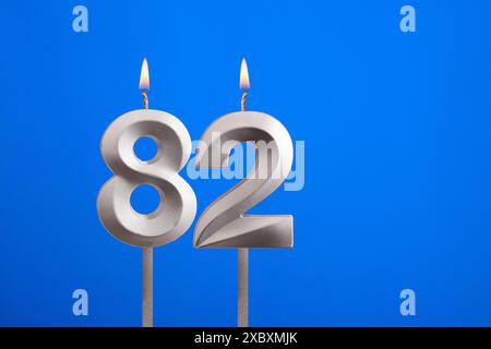 Birthday number 82 - Candle lit on blue background Stock Photo