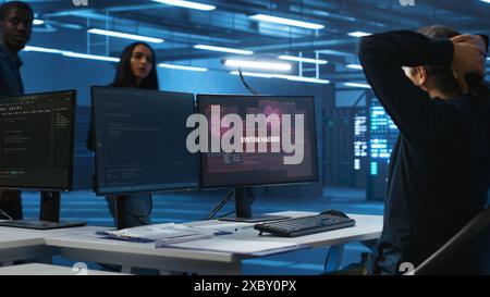Programmer in server hub workspace requesting assistance from colleagues during hacking attack on computers. Software developer asking for help from colleagues to protect data from unauthorized access Stock Photo