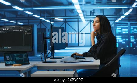 Computer scientist working in high tech server hub capable of processing vast amounts of data. Woman at PC desk typing on keyboard, updating servers controlling network resources Stock Photo