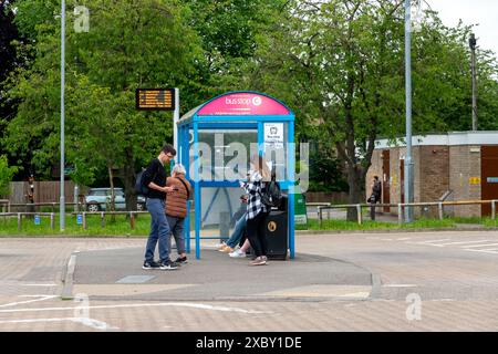 A bus stop bus shelter with digital sign and people waiting at Addenbrookes Hospital bus station Stock Photo