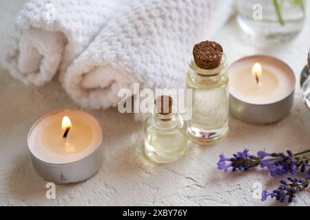 Bottles of aromatherapy essential oil with lavender flowers, candles and spa treatment accessories on white background Stock Photo