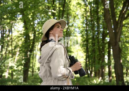 Forester with binoculars examining plants in forest Stock Photo