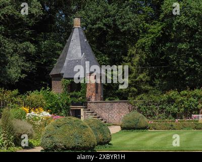 Well-kept garden with hedges and fountain as well as a small brick house and trees in the background, ochtrup, muensterland, germany Stock Photo