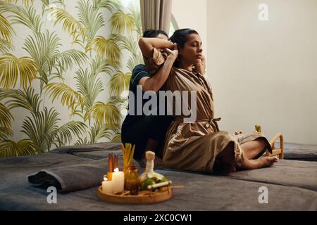 Woman in silk robe enjoying back stretch in spa salon Stock Photo