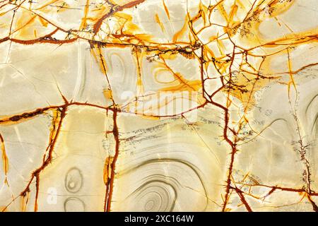 Surface of a beautiful stone, natural abstract pattern of yellow, brown and green stripes, lines, cracks and stains. Stock Photo