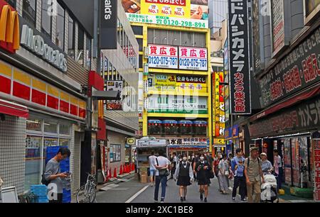 Local people in bustling pedestrianised backstreet of varied commercial outlets including McDonalds: Nishi-Shinjuku, Shinjuku-ku, Tokyo. May 2024 Stock Photo