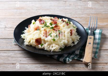 Slovak potato dumplings halusky with steamed sauerkraut and bacon on wooden table Stock Photo