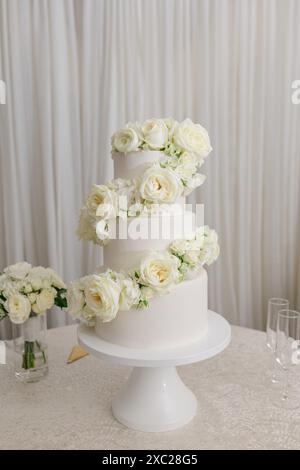 White tiered wedding cake with white roses Stock Photo