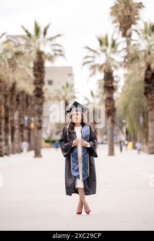 Women smiling in her graduation cap and gown looking to the side Stock Photo